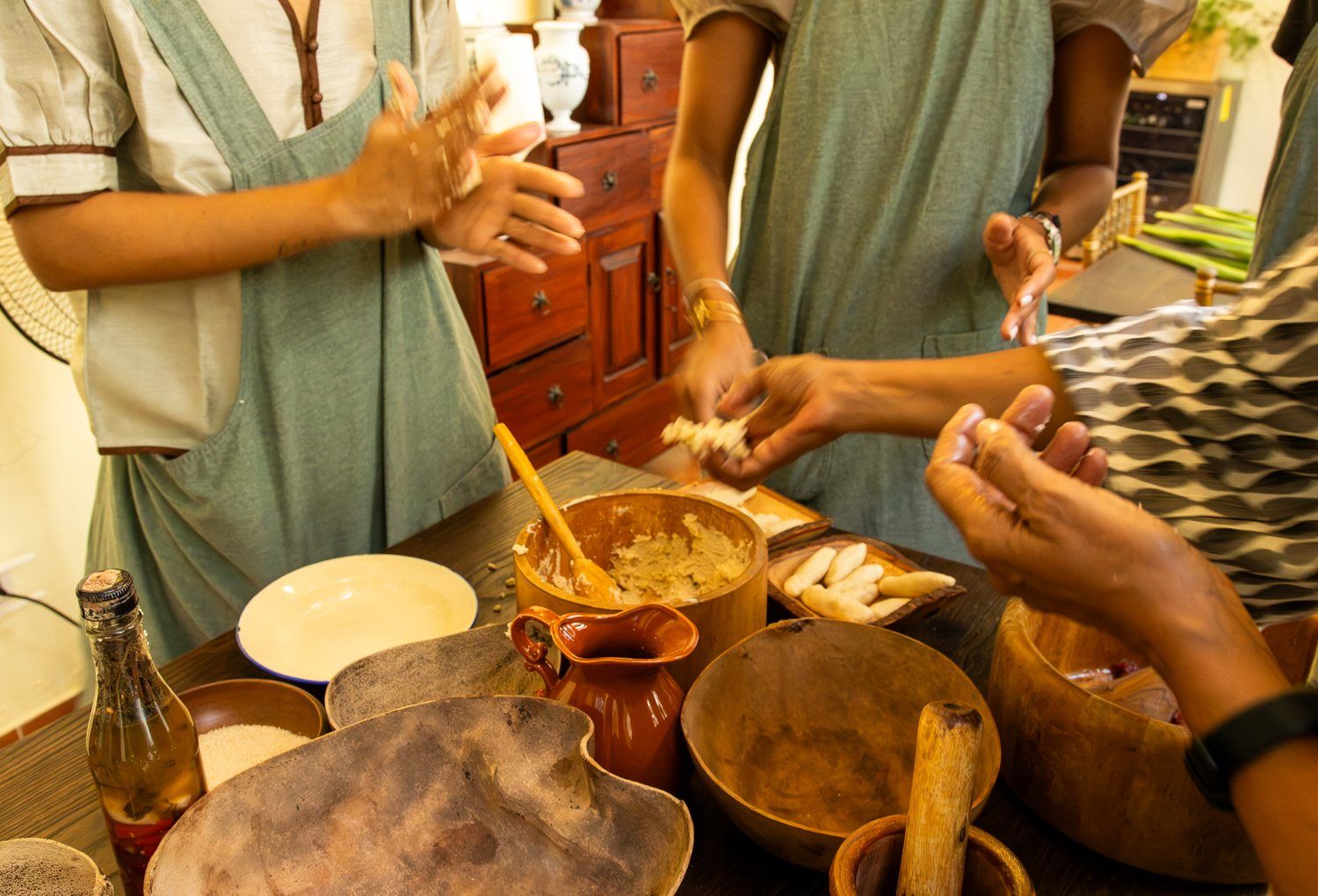 Manos que preparan ingredientes en vasijas de barro y de madera