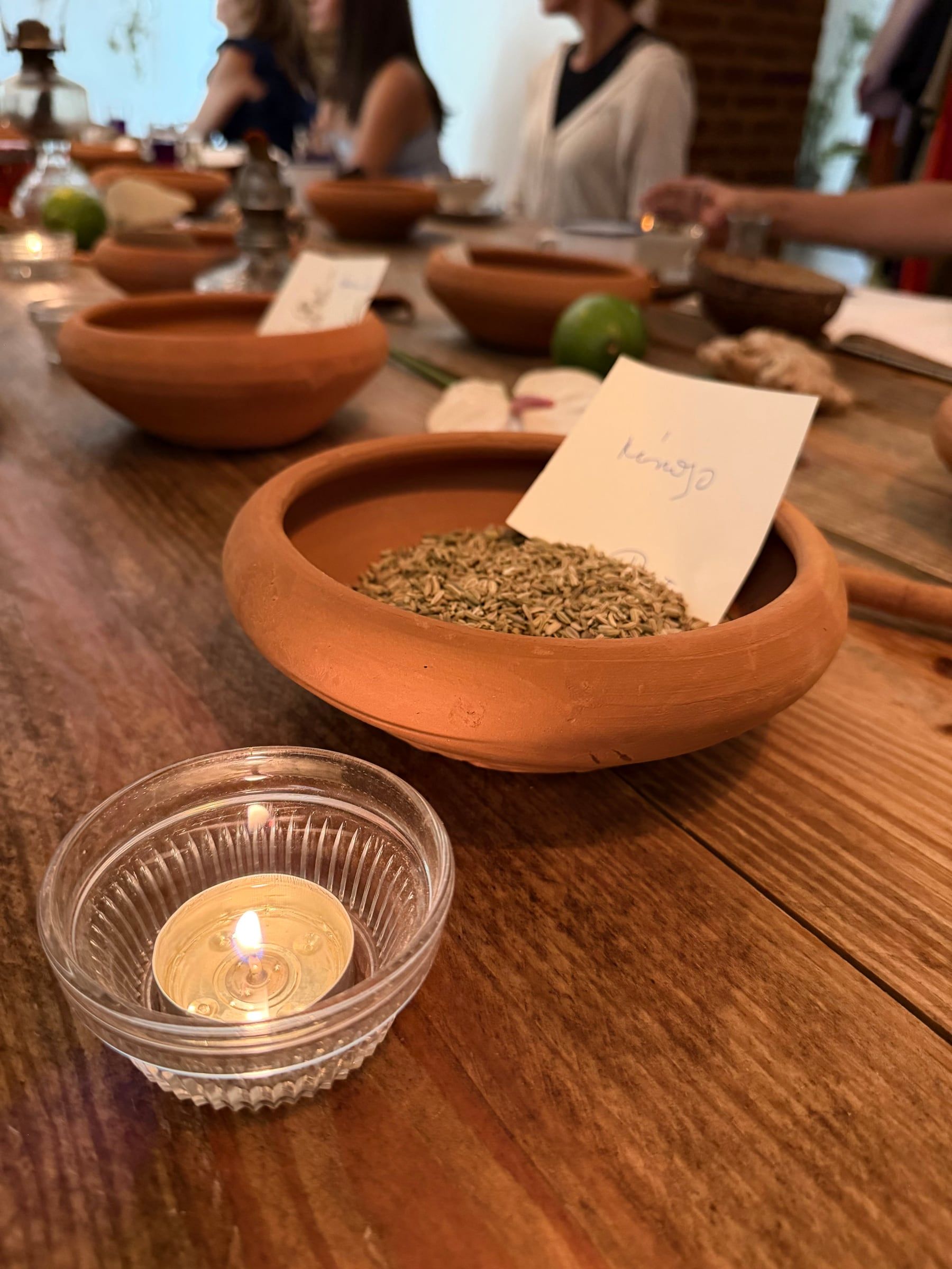 Cuencos de barro con especias y una vela encendida sobre la mesa de madera